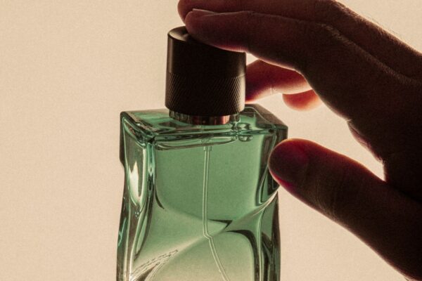 Dłoń trzymająca zielony flakon perfum